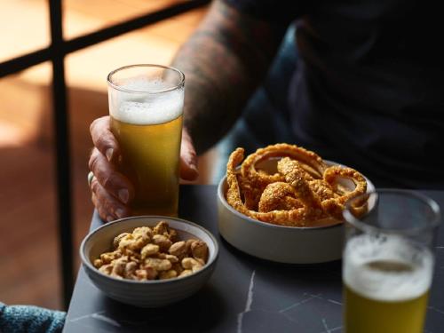 a person holding a glass of beer and onion rings at Kyah in Blackheath
