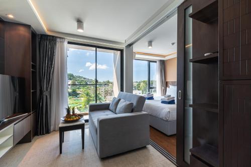 a bedroom with a couch and a bed and a window at Aristo 1 Phuket in Phuket Town