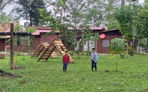 two boys standing in a yard with a playground at ECO HOTEL LACHUA in Cobán