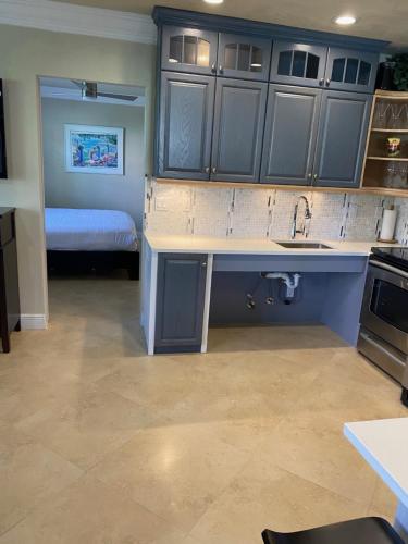 a kitchen with blue cabinets and a sink and a bed at Atlantic Shores Vacation Villas in Palm Beach Shores