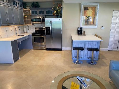a kitchen with a stainless steel refrigerator and a table at Atlantic Shores Vacation Villas in Palm Beach Shores