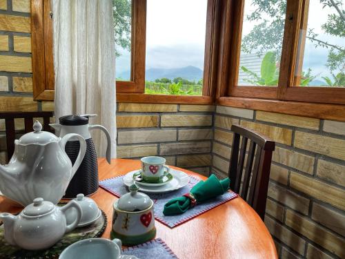 a table with a tea set on it with a window at Chalé de Pedra Recanto Verde dos Canyons in Praia Grande