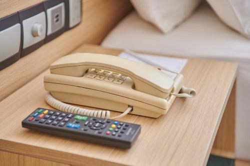 a phone on a table next to a remote control at Cititel Mid Valley in Kuala Lumpur