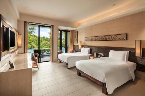 a hotel room with two beds and a television at Wanda Realm Resort Sanya Haitang Bay in Sanya