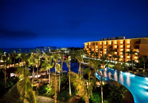 三亞的住宿－三亚海棠湾万达嘉华度假酒店，夜间有游泳池和棕榈树的酒店