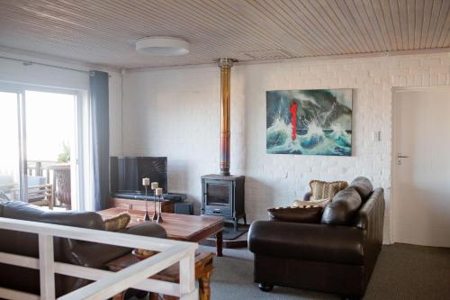 sala de estar con muebles de cuero y estufa de leña en Villa Del Mar, en Clareport