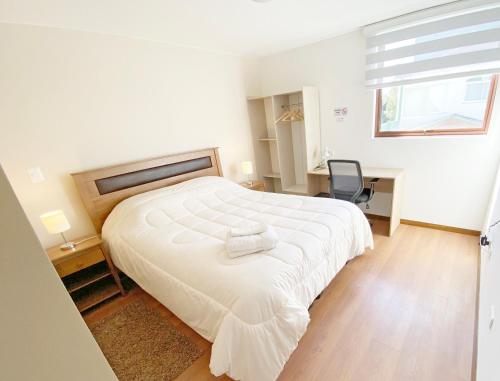 1 dormitorio con 1 cama blanca grande y 1 silla en Hostal Buró, en Concepción
