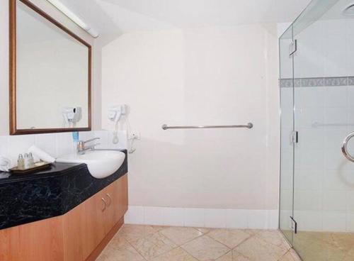 a white bathroom with a sink and a shower at Beach apartment with all the facilities you need - Landmark Resort in Mooloolaba