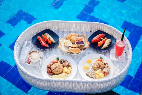 - un plateau de nourriture sur une table à côté de la piscine dans l'établissement Canggu Dream Village Hotel and Suites, à Canggu