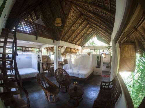 a bedroom with a bed and chairs in a room at Una Posada Mas in Mazunte