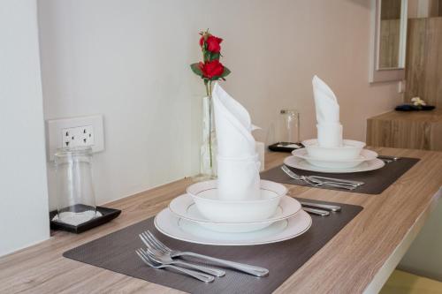 - une table avec deux plats blancs et une rose dans l'établissement Journey Residence Phuket, à Bang Tao Beach