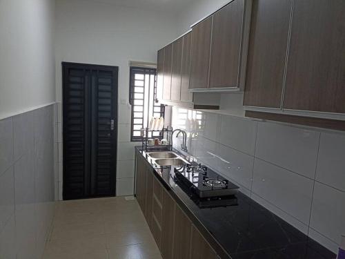 a kitchen with brown cabinets and a sink in it at Mulberi Homestay 4BR 3Bth(8-10 px) in Port Dickson