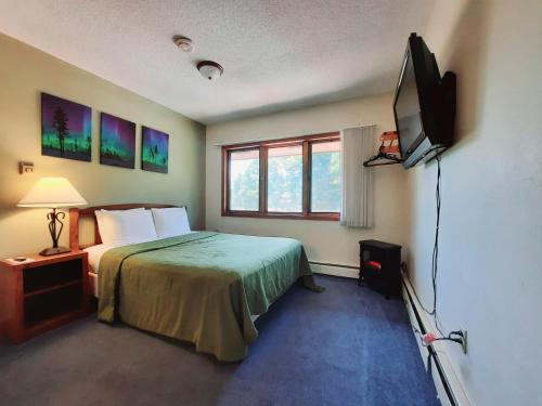 a bedroom with a bed and a flat screen tv at North Ironwood Acres - Black River Lodge in Ironwood