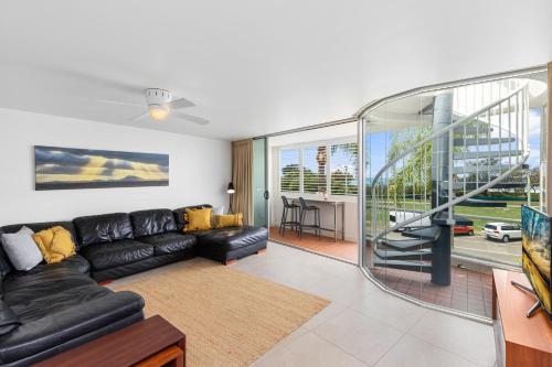a living room with a black leather couch and a balcony at Sundeck Gardens in Maroochydore