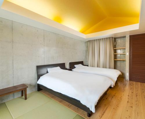 two beds in a room with a yellow ceiling at Asahinoyado Shidakaji in Nanjo