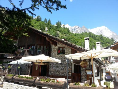 a building with umbrellas in front of it with mountains at Hotel Pilier D'Angle & Wellness in Courmayeur