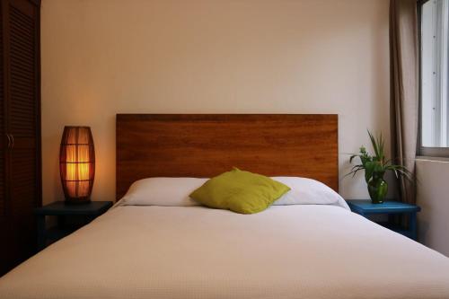 a bedroom with a bed with a green pillow on it at Hotel Villas Colibrí Suites & Bungalows in Cozumel