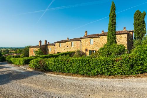 a large brick house with trees on the side of a road at Piccolo Borgo Gagnoni in Sinalunga