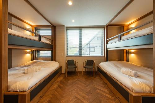 two bunk beds in a room with two chairs at Zai-On in Kutchan