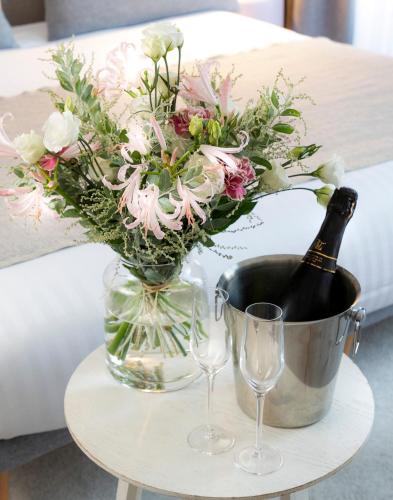 - une table avec une bouteille de champagne et un vase avec des fleurs dans l'établissement Hotel le Lapin Blanc, à Paris
