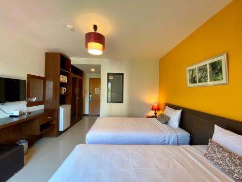 a hotel room with two beds and a television at WE Valley Hotel in Chiang Mai