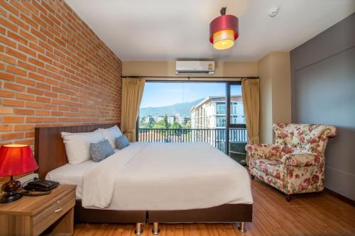 um quarto com uma cama grande e uma cadeira em WE Valley Hotel em Chiang Mai