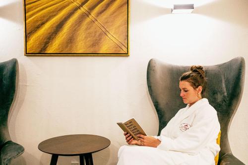 a woman sitting in a chair reading a book at Hotel Gotthard in Lech am Arlberg