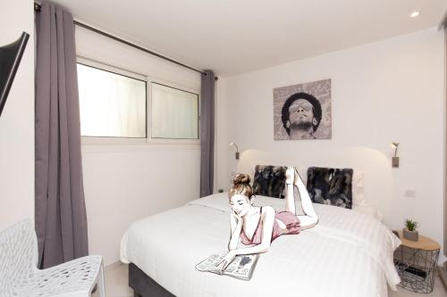 Une fille est assise sur un lit dans une chambre dans l'établissement Brand new 2 bedrooms next to Croisette !, à Cannes
