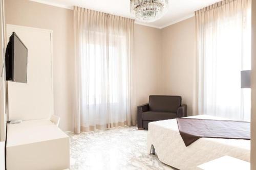 a white bedroom with a bed and a chair at Faro Bianco Gallipoli - Suites & Apartments in Gallipoli