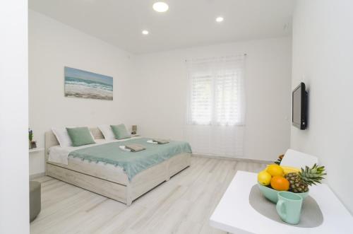 a white room with a bed and a table with a bowl of fruit at Apartment Rafaello in Dubrovnik