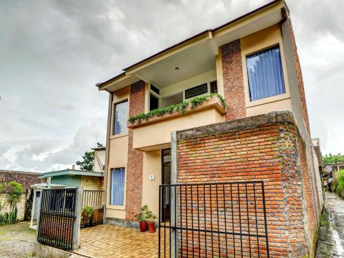 une maison en briques avec un portail en face de celle-ci dans l'établissement Super OYO 90828 Ara Guest House, à Batu