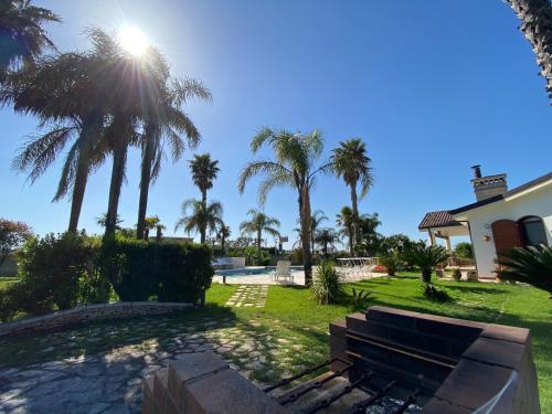 a park with palm trees in front of a building at VILLA ADA pool residence in Veglie