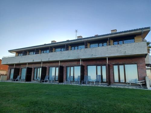 un edificio con ventanas y sillas en el césped en La Venta del Mar, en Liencres