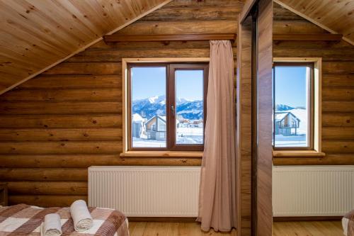 a bedroom with two windows in a wooden house at Snow Time Eco Chalet in Gudauri