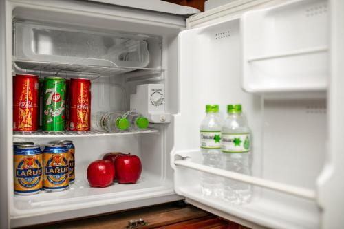 an open refrigerator filled with soda cans and apples at Hoi An Riverside Villas & Apartments in Hoi An