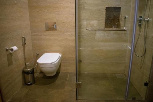 a bathroom with a toilet and a glass shower at Altrude By The Sea in Candolim