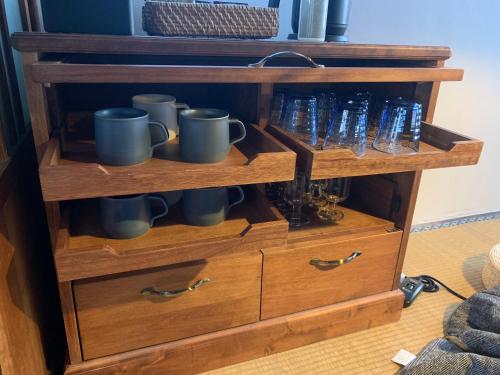 a wooden cabinet with mugs and cups on it at uminca ウミンカ in Numazu