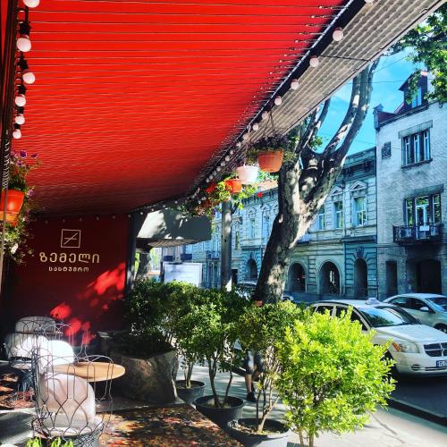 a restaurant with a red roof and some trees and buildings at Zemeli Boutique Hotel by DNT Group in Tbilisi City