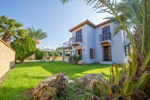 a house with a yard with palm trees at The Olympians Villas in Polis Chrysochous