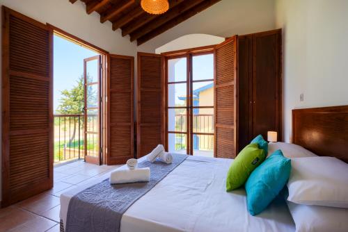 sypialnia z dużym łóżkiem z niebieskimi i zielonymi poduszkami w obiekcie The Olympians Villas w mieście Polis Chrysochous