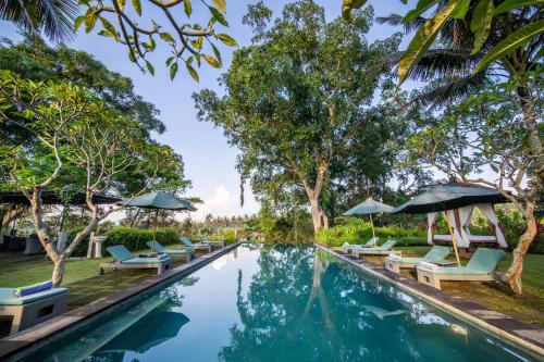 a pool at the resort with lounge chairs and umbrellas at The Hidden Paradise Ubud - CHSE Certified in Ubud