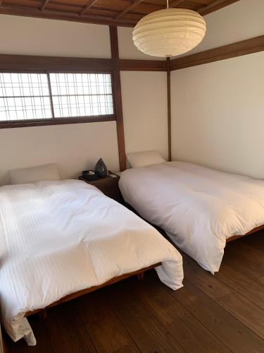 two beds in a room with two windows at uminca ウミンカ in Numazu