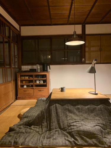 a room with a table and a lamp and a kitchen at uminca ウミンカ in Numazu