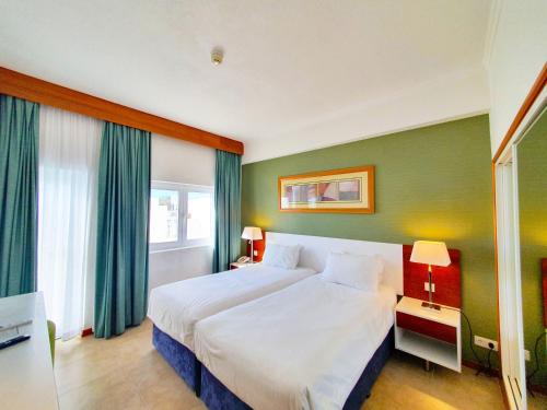 
a hotel room with a large bed and a large window at Holiday Inn Algarve - Armação de Pêra, an IHG Hotel in Armação de Pêra
