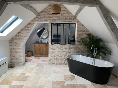 uma casa de banho com uma banheira preta no meio de um quarto em La Charmeraie Wellness & SPA em Lacroix-Saint-Ouen