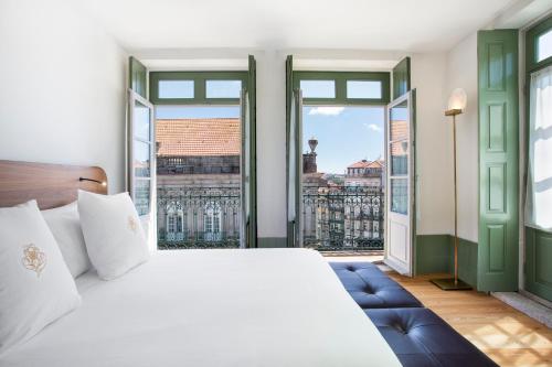 a bedroom with a large bed and large windows at One Shot Aliados Goldsmith 12 in Porto
