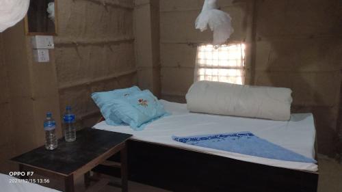 a bed in a room with a pillow and a table at Bardia Community Homestay in Bardiyā