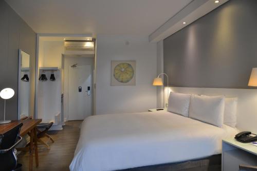 a bedroom with a large white bed and a desk at ANEW Hotel Roodepoort Johannesburg in Roodepoort