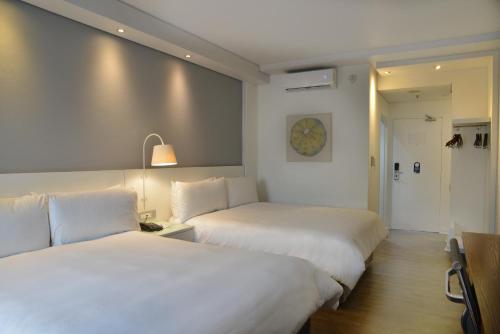 two beds in a hotel room with white sheets at ANEW Hotel Roodepoort Johannesburg in Roodepoort