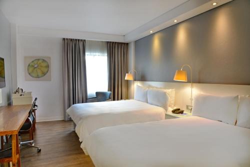 a hotel room with two beds and a desk at ANEW Hotel Roodepoort Johannesburg in Roodepoort
